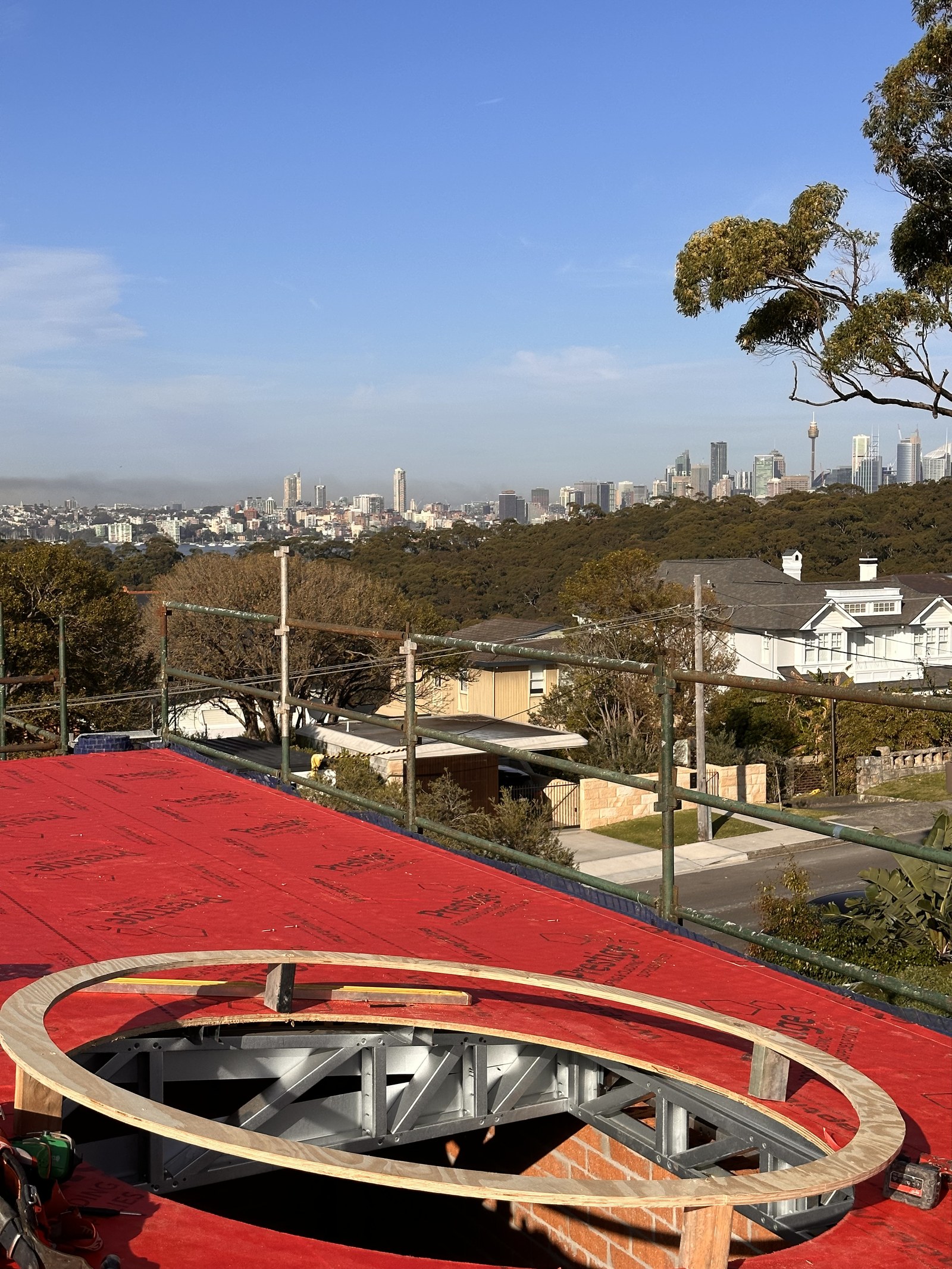 Round skylight installation on roof, Mosman, with Sydney city skyline view